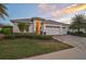 Elegant single-story home with a three-car garage and mature landscaping creating an inviting entrance at 8261 Grande Shores Dr, Sarasota, FL 34240