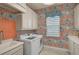 Vibrant laundry room with patterned wallpaper, modern appliances, white cabinetry, and ample counter space at 8261 Grande Shores Dr, Sarasota, FL 34240