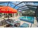 Inviting screened pool area featuring lounge chairs, umbrella, and outdoor seating at 8261 Grande Shores Dr, Sarasota, FL 34240