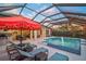 Resort-style screened pool and spa with a red umbrella and plenty of space for entertaining at 8261 Grande Shores Dr, Sarasota, FL 34240