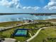 Aerial view of community tennis courts by a lake, with walking path and lush landscaping at 8261 Grande Shores Dr, Sarasota, FL 34240