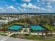 Aerial view of community tennis courts in a residential neighborhood with lush landscaping and sunny skies at 8261 Grande Shores Dr, Sarasota, FL 34240