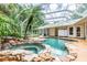 Relaxing pool and spa area with rock landscaping and screened enclosure at 1101 Anclote Blvd, Tarpon Springs, FL 34689