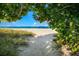 Sandy pathway under beach foliage leading to the shore at 176 Avens Dr, Nokomis, FL 34275