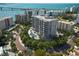 Stunning aerial view of condo building featuring a pool, palm trees, and picturesque bay views at 325 Golden Gate Pt # 704, Sarasota, FL 34236