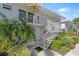 Ground level condo exterior, featuring stairs, balcony, and tropical landscaping at 521 W Venice Ave # 22, Venice, FL 34285