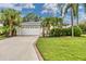 House exterior featuring a white garage door, lush landscaping, and palm trees at 6650 Cheswick St, Sarasota, FL 34243