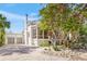Two-story white house with a screened porch, gray garage doors, and brick driveway at 689 Lands End Dr, Longboat Key, FL 34228