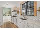 White kitchen with marble countertops, farmhouse sink, and light wood floors at 689 Lands End Dr, Longboat Key, FL 34228