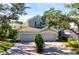 Tan three-car garage home with lush landscaping and brick driveway at 7484 Botanica Pkwy # 101 B-24, Sarasota, FL 34238