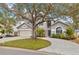 Two-story house with a gray exterior, paved driveway, and large tree at 7737 40Th E Ct, Sarasota, FL 34243
