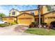 Front view of a two-story townhome with yellow exterior, two-car garage, and nicely landscaped front at 8115 Miramar Way # 202, Lakewood Ranch, FL 34202