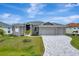 Gray three-car garage home with landscaping and paver driveway at 10442 Winnipeg St, Port Charlotte, FL 33981