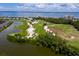 Aerial view of a golf course surrounded by waterfront homes and condos with beautiful blue water in the background at 2550 Harbourside Dr # 322, Longboat Key, FL 34228