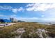 Beach with covered picnic areas and grass leading to residential buildings on the horizon at 2550 Harbourside Dr # 322, Longboat Key, FL 34228