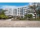 Exterior view of a modern white condo building with landscaped grounds and a covered entrance at 2550 Harbourside Dr # 322, Longboat Key, FL 34228