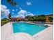 Large pristine swimming pool surrounded by lounge chairs, palm trees, and a clubhouse with a tile roof on a sunny day at 2550 Harbourside Dr # 322, Longboat Key, FL 34228