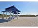 Beach pavilion featuring blue picnic tables, sun shelter, and sandy pathways leading to the beach at 3131 Bayou Sound, Longboat Key, FL 34228