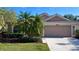 Beige house with two-car garage, landscaping, and palm trees at 8773 Stone Harbour Loop, Bradenton, FL 34212