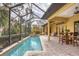 Inviting pool area with covered patio, lush landscaping, and outdoor dining space at 135 N Creek Ln, Osprey, FL 34229