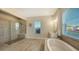 Relaxing bathroom with soaking tub, walk-in shower, and large mirror at 15009 18Th E Run, Parrish, FL 34219