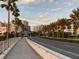 Road scene with palm trees, pedestrian walkway, and city buildings in the background at 1604 Stickney Point Rd # 102, Sarasota, FL 34231