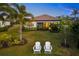 Two white Adirondack chairs in a grassy backyard, near a house at 275 Toscavilla Blvd, Nokomis, FL 34275