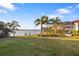 Lakefront backyard with grassy area and palm trees at 275 Toscavilla Blvd, Nokomis, FL 34275