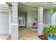 Covered front porch with tiled flooring, two armchairs, and decorative plants at 2831 Whispering Pine Ln, North Port, FL 34287