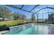 Relaxing screened-in pool with a waterfall feature and tranquil views at 7872 Mainsail Ln, Sarasota, FL 34240