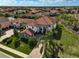 Aerial view of a home with a red tile roof, brick driveway, and green lawn at 13408 Swiftwater Way, Bradenton, FL 34211