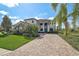 Beautiful home with a brick driveway, lush landscaping, and elegant architectural details creating a warm and inviting facade at 13408 Swiftwater Way, Bradenton, FL 34211