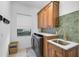 Laundry room with wooden cabinets, green tile, and a sink at 13408 Swiftwater Way, Bradenton, FL 34211