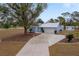 Cute light blue house with a large tree and long driveway at 15026 Dania Ave, Port Charlotte, FL 33953