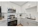 Modern kitchen with white cabinets, stainless steel appliances, and a corner sink at 1703 N Tamiami Trl # 209, Sarasota, FL 34234