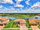 Aerial view of the home showcasing lake views, lush landscaping, and tile roof at 20686 Valprato Ct, Venice, FL 34293