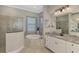 Well-lit bathroom featuring a large soaking tub, tiled shower, and white vanity with granite countertops at 20686 Valprato Ct, Venice, FL 34293