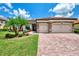 Home exterior featuring a brick driveway, a two-car garage and manicured landscaping at 20686 Valprato Ct, Venice, FL 34293