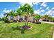 Manicured front lawn with palm trees and lush landscaping enhance this home's curb appeal at 20686 Valprato Ct, Venice, FL 34293