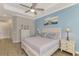 This comfortable main bedroom includes wood floors, a ceiling fan, bedside lamps, and coastal decor at 20686 Valprato Ct, Venice, FL 34293