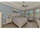 Comfortable main bedroom features a ceiling fan, wood floors, and large windows with a waterfront view at 20686 Valprato Ct, Venice, FL 34293