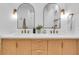 Modern bathroom with double vanity, arched mirrors, and light wood cabinets at 2226 Arlington St, Sarasota, FL 34239