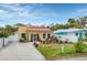 Cute yellow house with a tile roof, landscaping, and a gravel driveway at 305 Pameto Rd, Nokomis, FL 34275