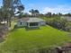 An aerial view shows the lush backyard featuring a well-maintained lawn, and screened-in lanai in a quiet neighborhood at 3151 Johannesberg Rd, North Port, FL 34288