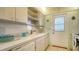 White kitchen with wood cabinets, a sink, and a door leading to outside at 3810 Gulf Of Mexico Dr # F302, Longboat Key, FL 34228