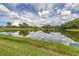 Serene lake view with lush landscaping and cloudy sky at 5405 Champagne # 59, Sarasota, FL 34235