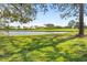 Backyard of the home with large pond in the distance beyond a green grassy lawn at 5724 Doral Dr, Sarasota, FL 34243