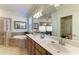 Bathroom with double vanity, large mirror, and a soaking tub at 20710 Saluti Pl, Venice, FL 34293