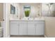 Double vanity bathroom with white cabinets, tile floors, and a glass-enclosed shower at 4831 Boston Common Gln, Bradenton, FL 34211