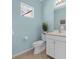 Light blue bathroom with white vanity, toilet, and small window at 4831 Boston Common Gln, Bradenton, FL 34211
